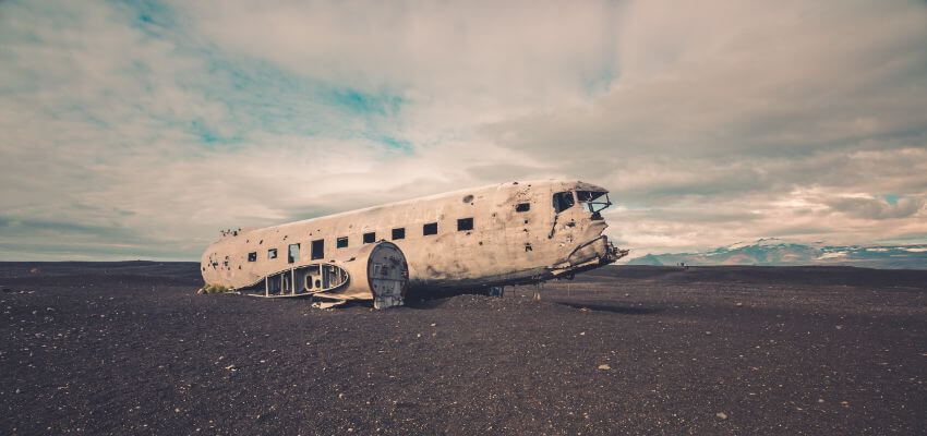 Ein Flugzeugwrack auf einem schwarzen Vulkan Boden.