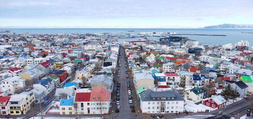 Bild von oben auf Reykjavik. Viele weiße kleine Häuser mit bunten Dächern sind zu sehen.