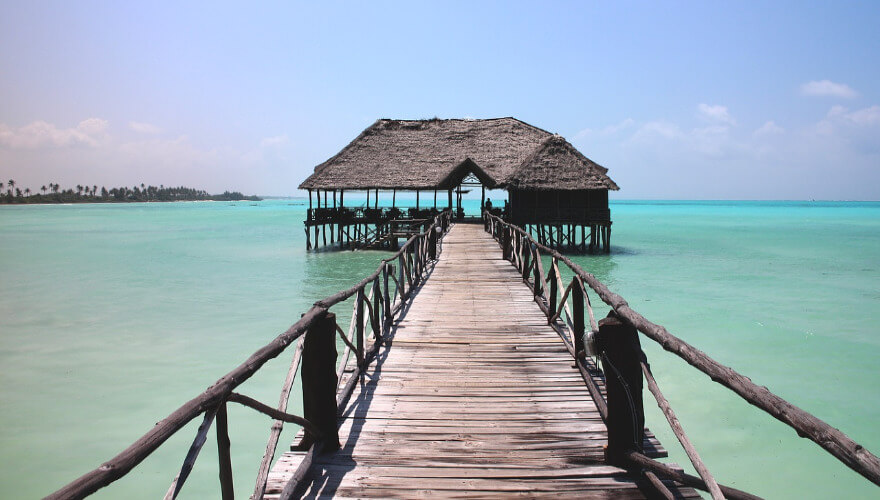 Ein alter rustikaler Steg der weit in Meer ragt und mit einer offen überdachten Hütte endet.