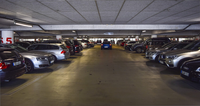 Ein volles Parkdeck, wobei ein blaues Auto Richtung Ausfahrt fährt.