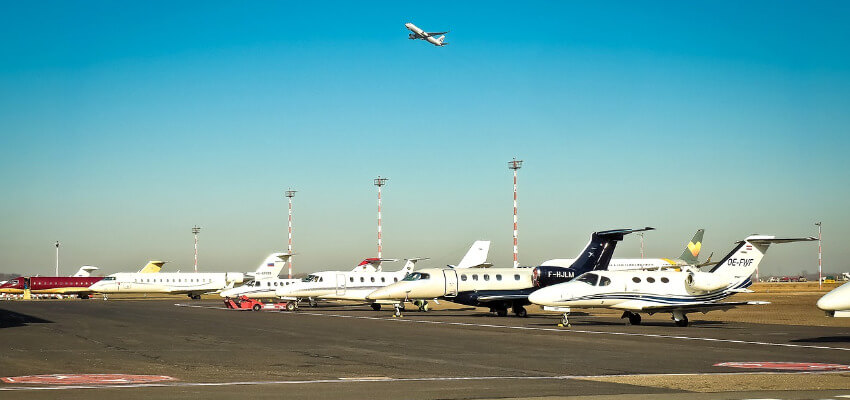 Mehrere Privatjets parken nebeneinader, nähe der Startbahn.