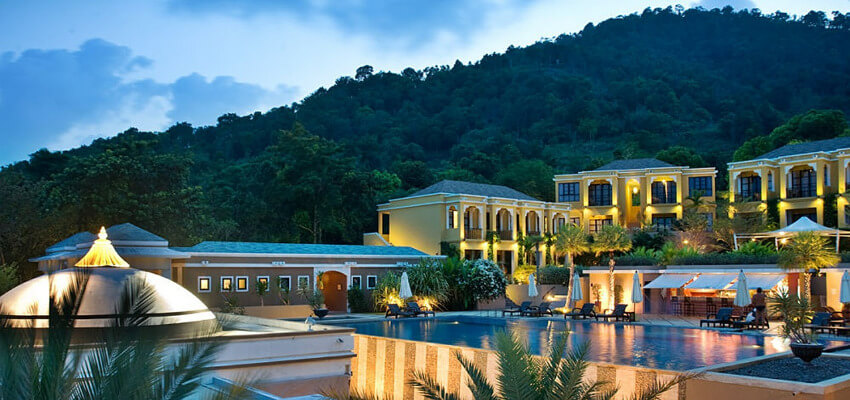 Ein Spa Hotel in der Abenddämmerung, wobei die Fassade des Hotels beleuchtet ist. Vor dem Hotel befindet sich ein Pool.