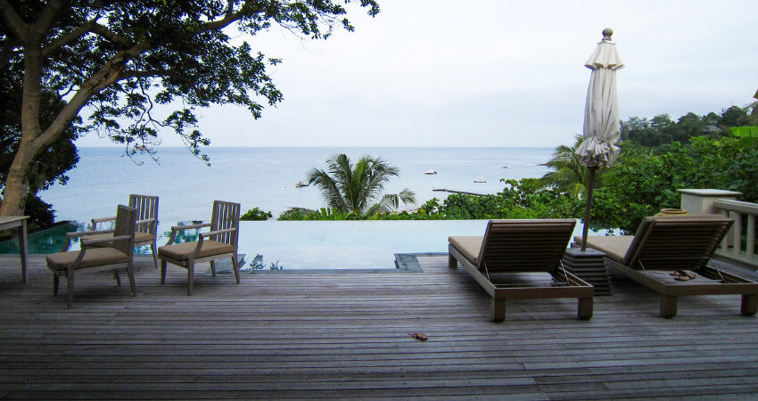 Eine Terrasse mit Liegestühlen und Sesseln mit Blick aufs Meer.