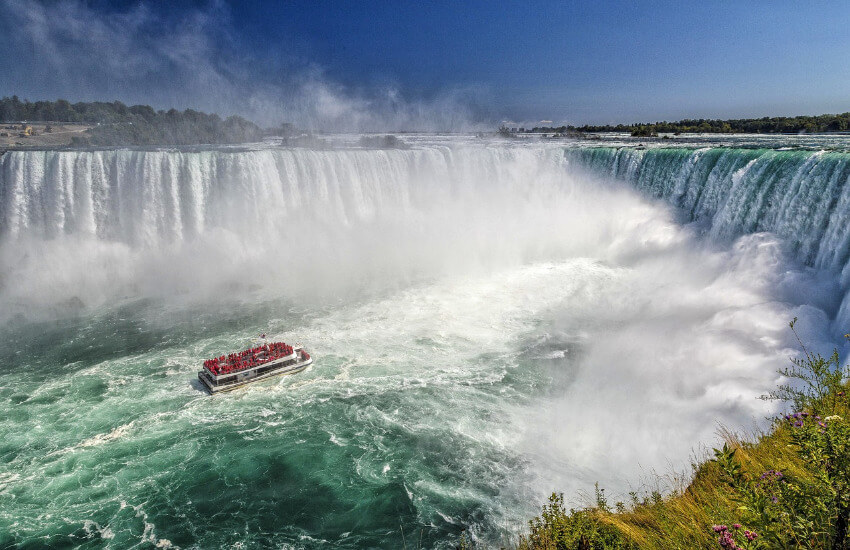 Ein Touristenboot steuert in die Nähe des mega Wasserfalls.