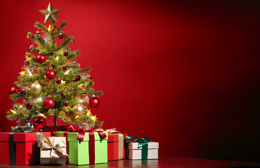Ein Weihnachtsbaum mit roten und goldenen Kugeln und Geschenken darunter.