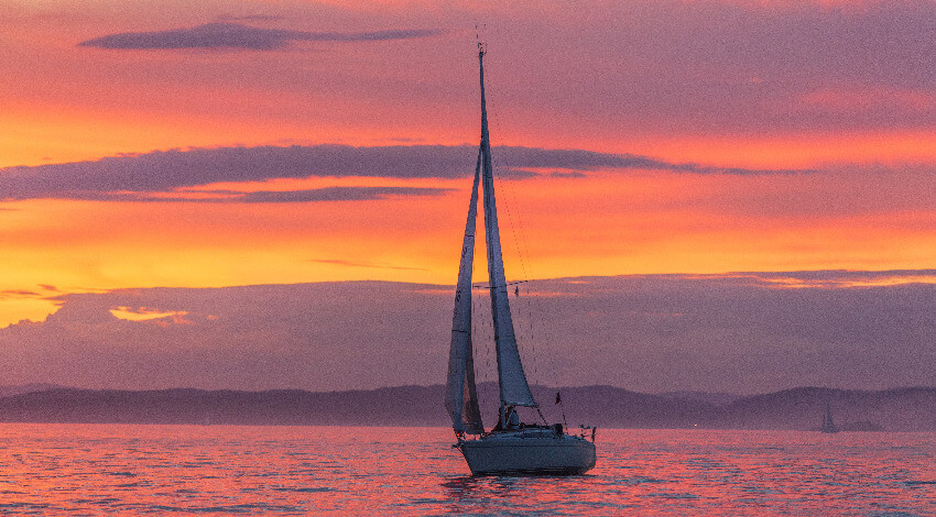 Eine Yacht auf offenem Meer im Abendrot.