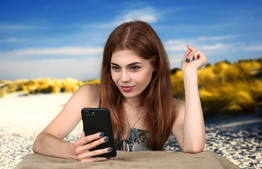 Eine junge Frau am Smartphone, um eine Reise zu buchen.