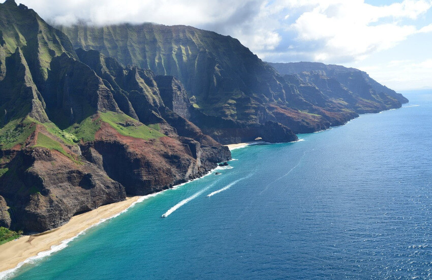Blaues Meer, steile Felsklippen und links unten im Bild ein schaler Streifen Sandstrand.