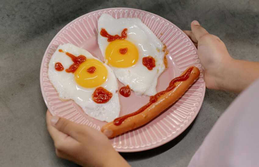 Ein Spiegelei und eine Wurst, die ein lachendes Smiley simulieren.