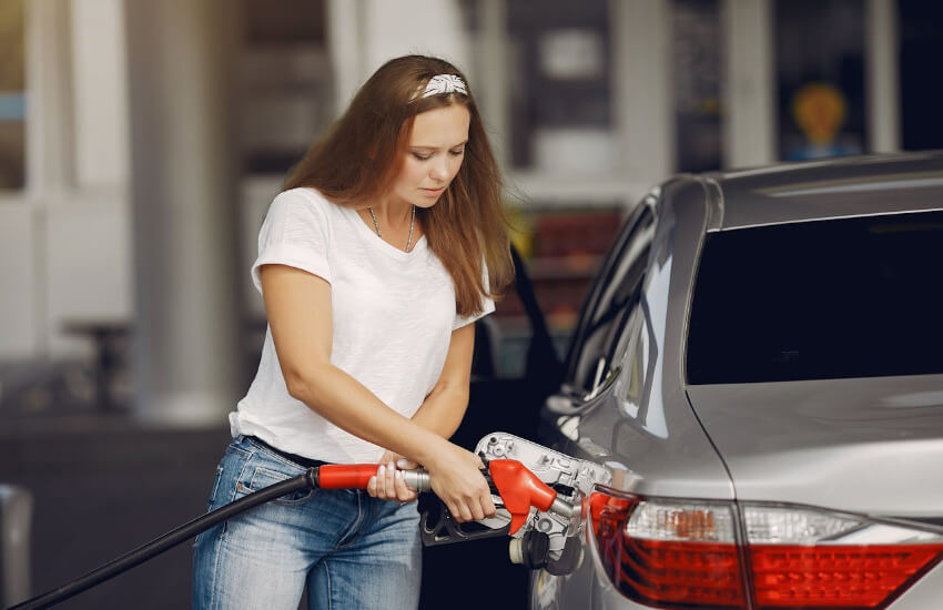 Eine Frau betankt ihr silbernes Auto.