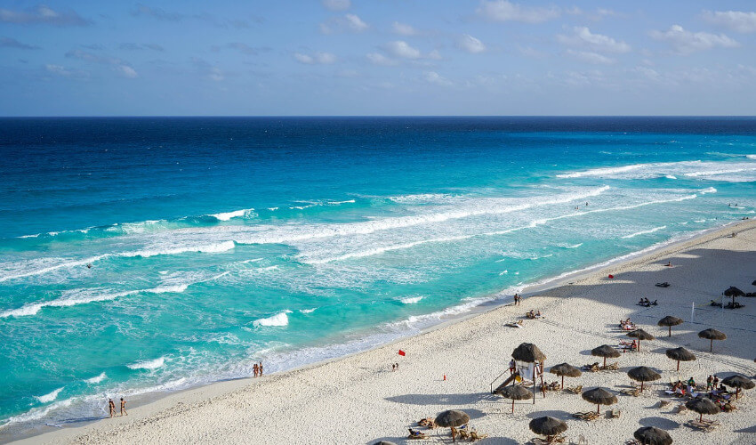Cancún Strand Luftaufnahme des Strandes von Cancún, Mexiko, mit türkisfarbenem Meer, Wellen, weißem Sand und Resorts unter blauem Himmel.